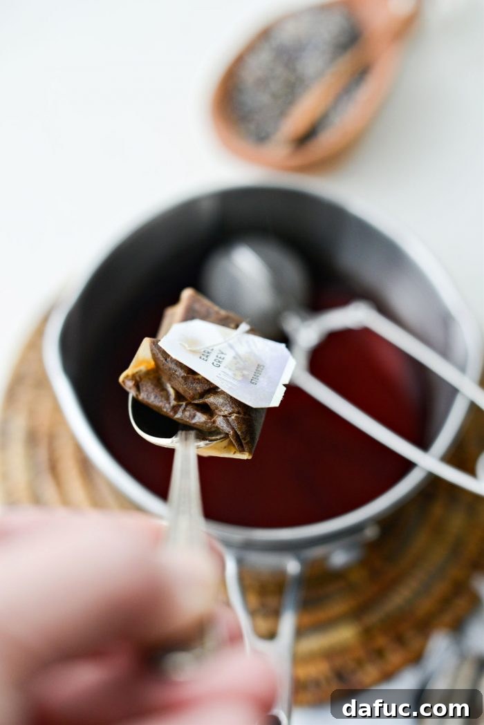 Removing the tea bag from the steeped Earl Grey tea, squeezing out excess liquid.