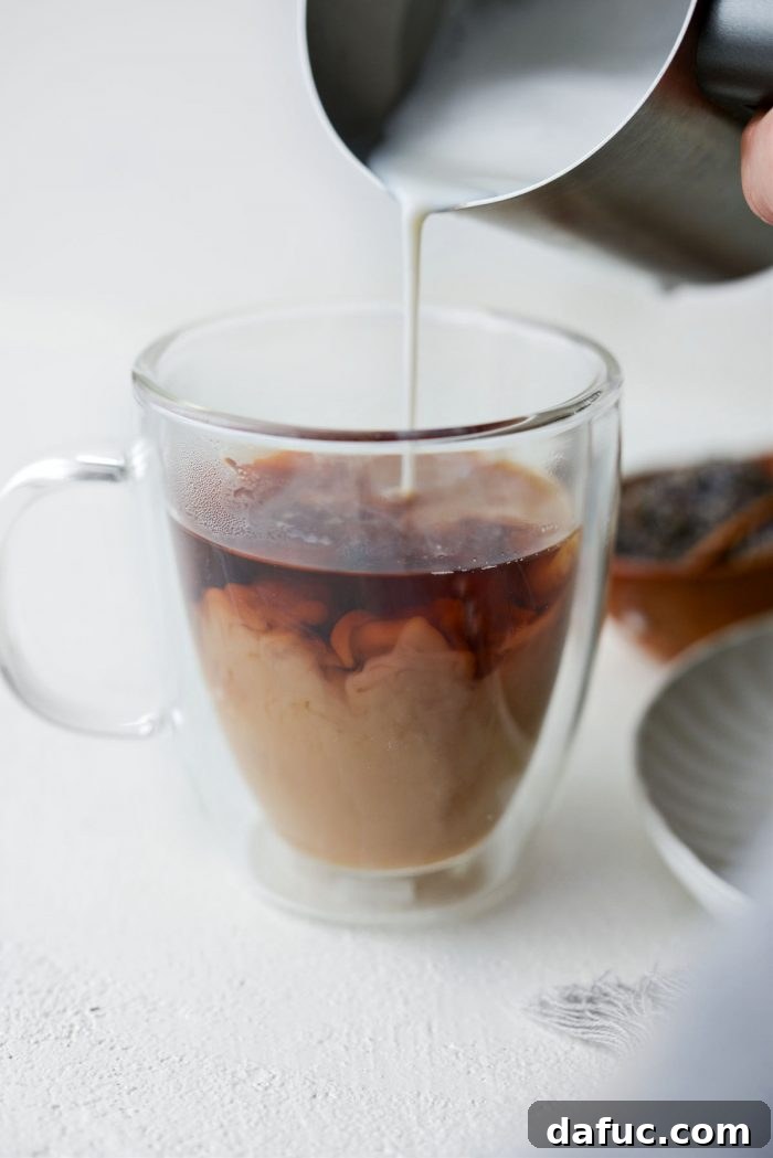 Pouring frothed milk into the steeped tea in a mug to create the London Fog effect.
