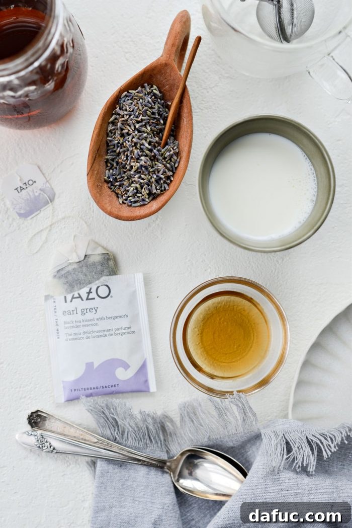 All the ingredients for a London Fog Tea Latte laid out: water, Earl Grey tea bag, culinary lavender, milk, and vanilla syrup.