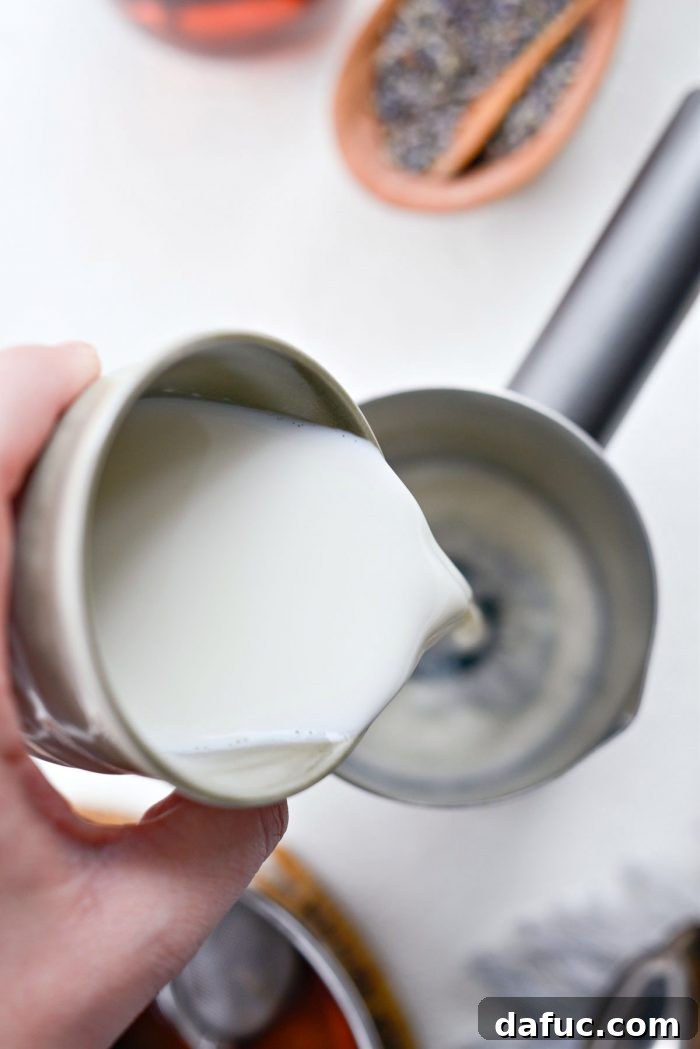 Milk and vanilla syrup being poured into a milk frother, preparing for the next step of the London Fog Tea Latte.