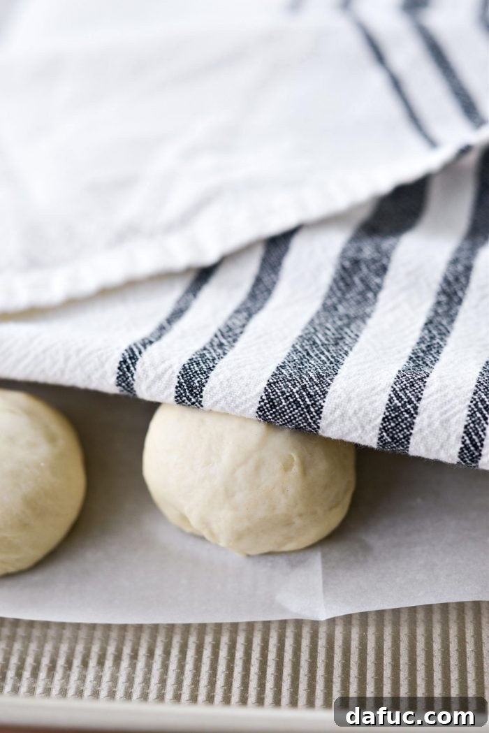Bite-Sized Pita Pockets 17 Shaped pita dough balls resting on parchment paper under a towel for 15 minutes
