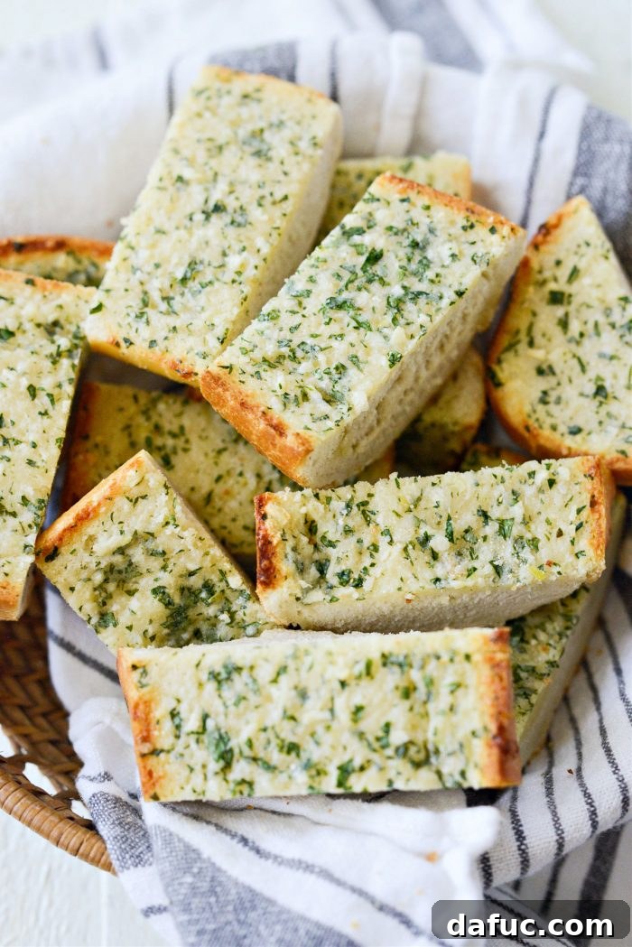 Two halves of freshly baked 15-Minute Garlic Bread on a baking sheet, golden brown and ready to be sliced