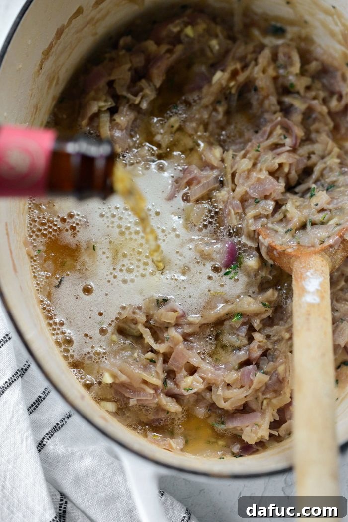 Pouring a bottle of beer into the Dutch oven with caramelized onions and roux.