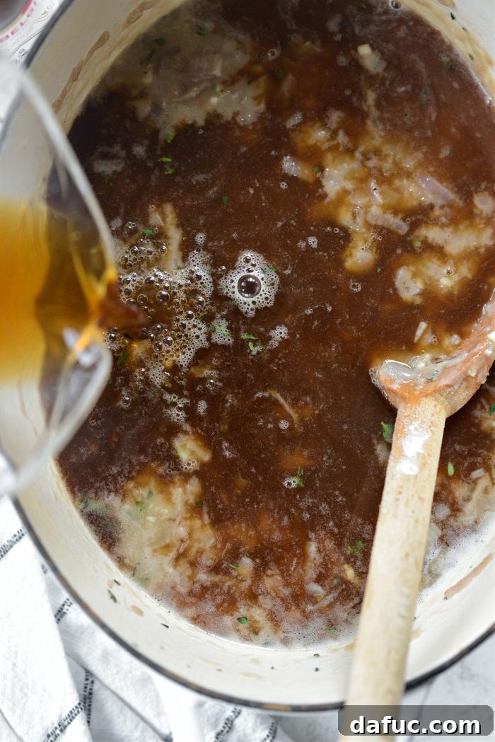 Adding unsalted beef stock to the onions and beer mixture in the Dutch oven.