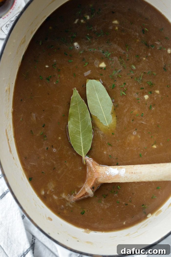 Two dried bay leaves dropped into the simmering French onion soup.
