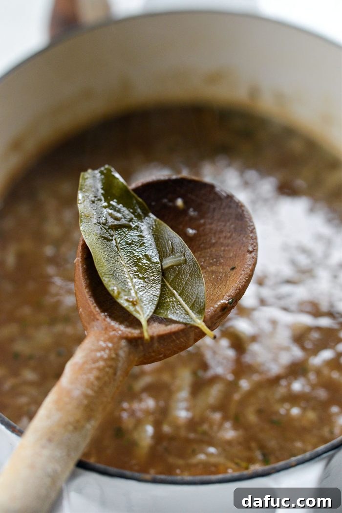 Removing bay leaves from the finished French onion soup before serving.