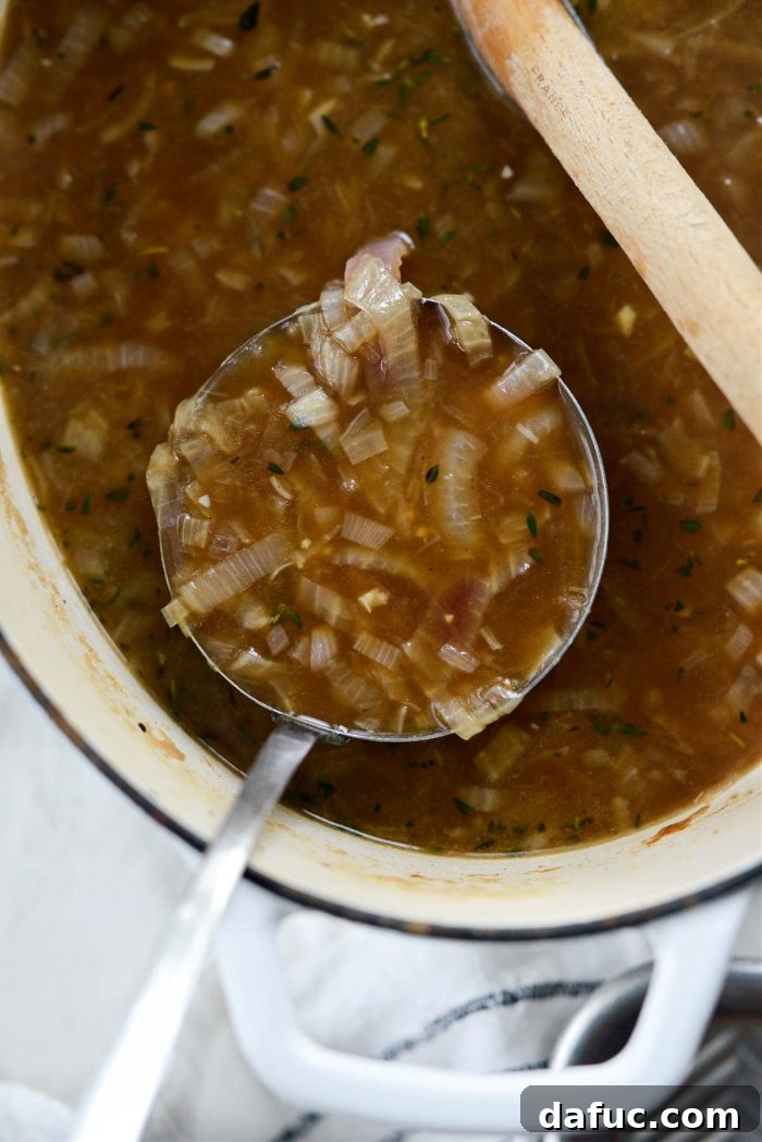 A ladle filled with rich Smoky Beer French Onion Soup.