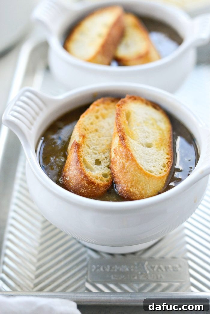 Toasted baguette slices placed on top of ladled French onion soup.