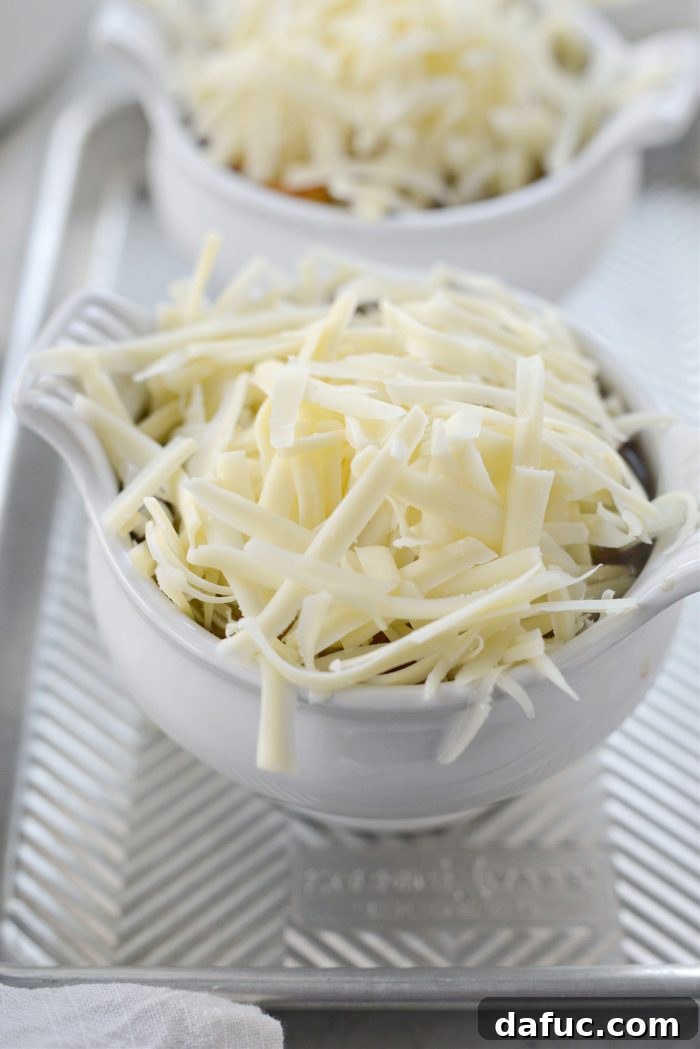 A mound of freshly grated Gruyère cheese covering the toasted baguette on top of the soup.