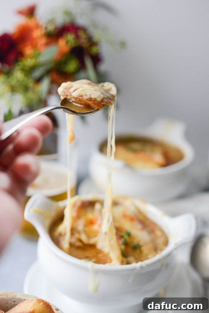 An irresistible cheese pull from a bowl of Smoky Beer French Onion Soup, showcasing the melted Gruyère.