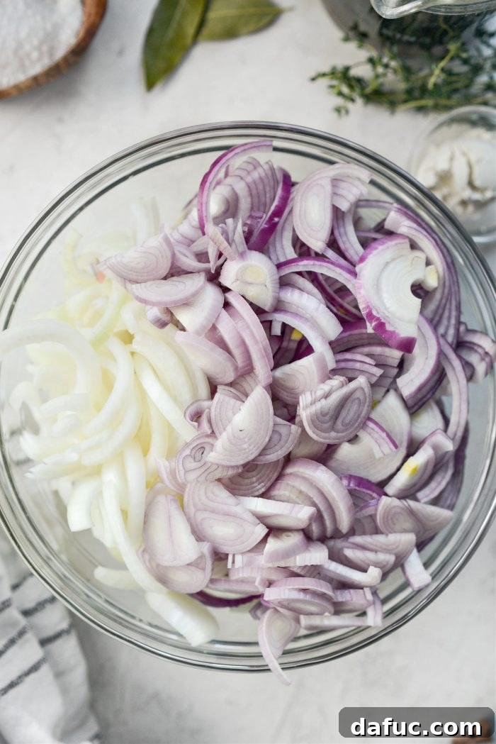 Three pounds of thinly sliced onions in a bowl, ready for caramelization.
