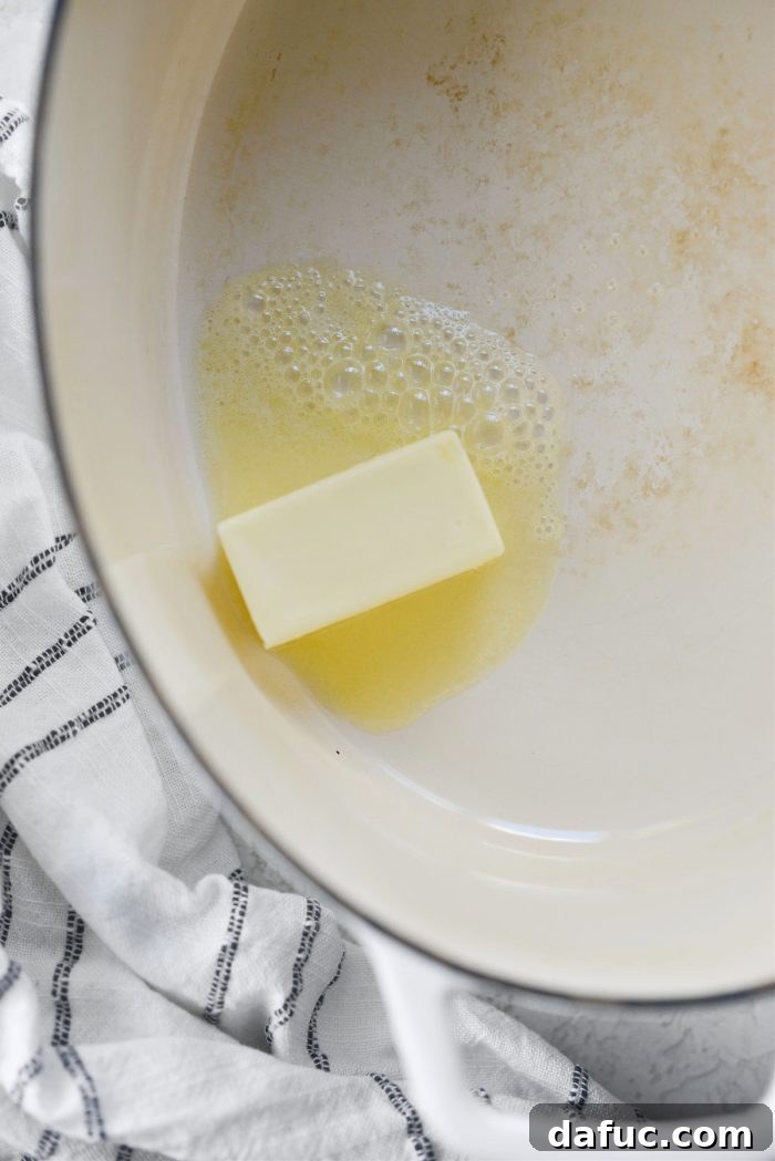 Melting unsalted butter in a large Dutch oven over medium-high heat.
