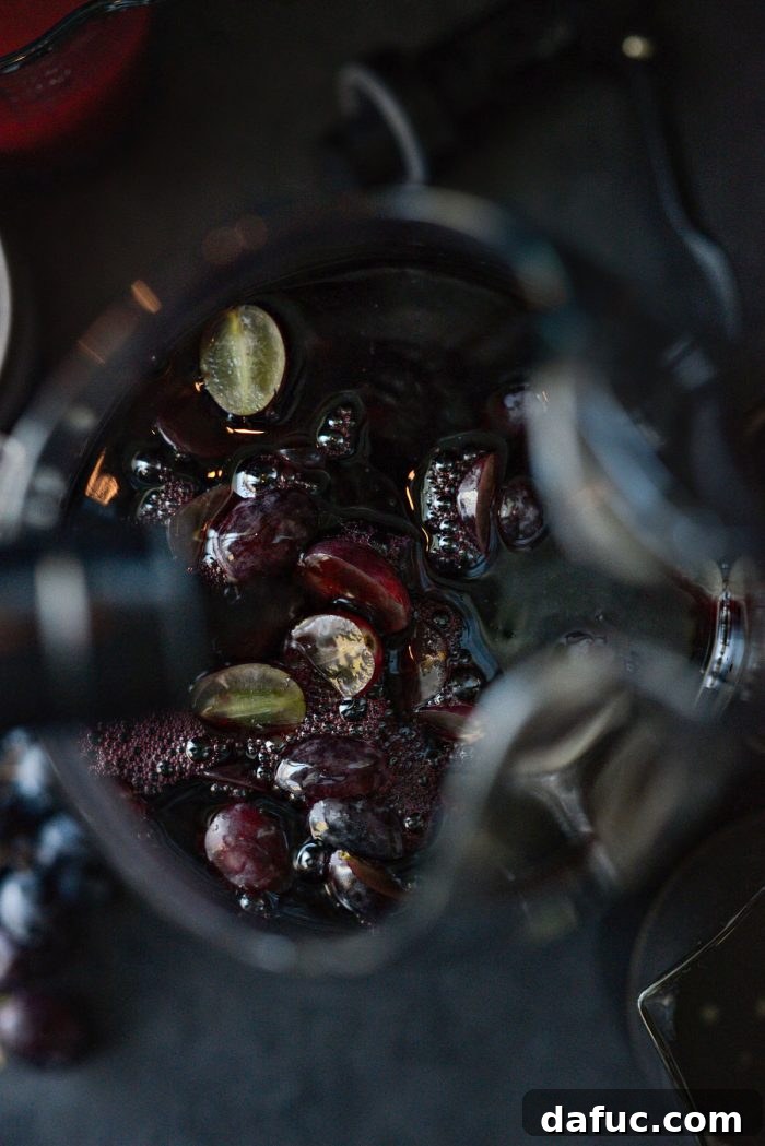 Pouring dark red wine into a pitcher with fruit