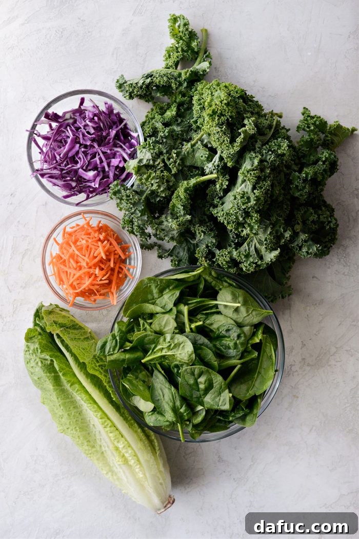 Fresh ingredients for My Go-To Kale Salad Blend laid out: kale, spinach, romaine, cabbage, and carrots.