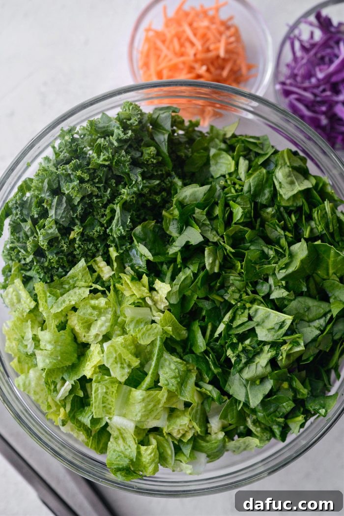 Chopped kale, spinach, and romaine lettuce in a very large mixing bowl, ready for combining.