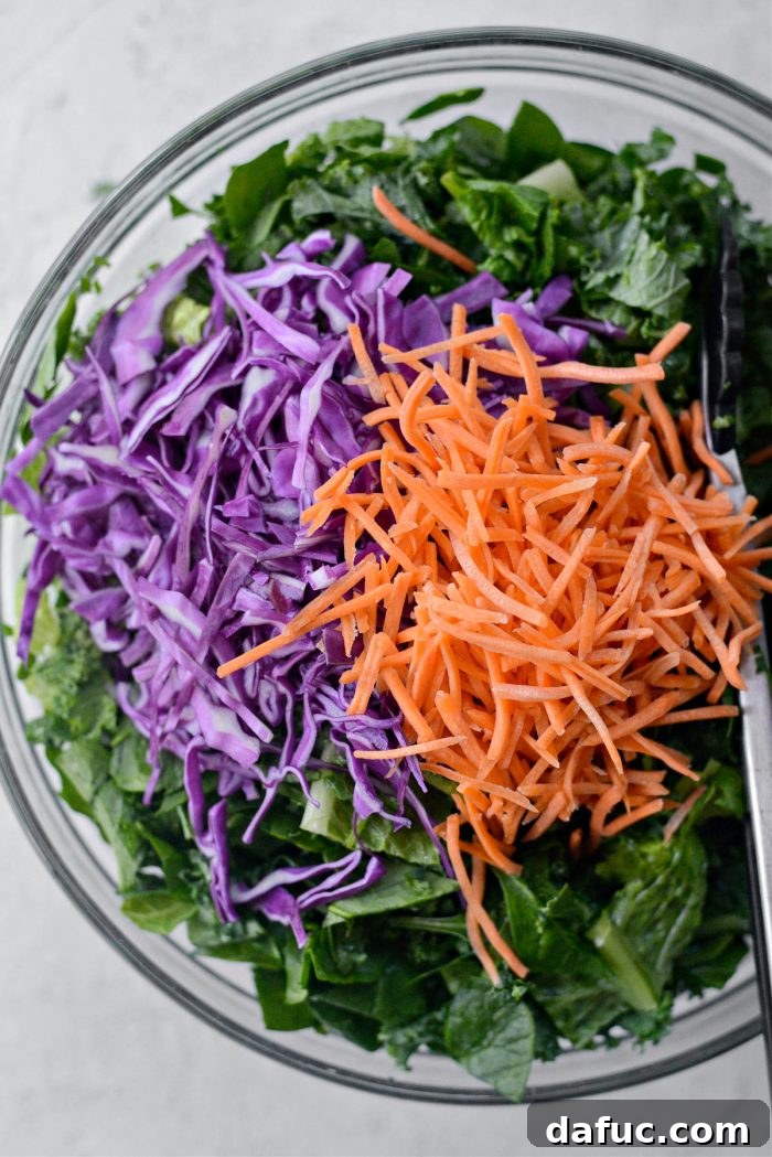 Thinly sliced purple cabbage and shredded carrots being added to the bowl of mixed greens.