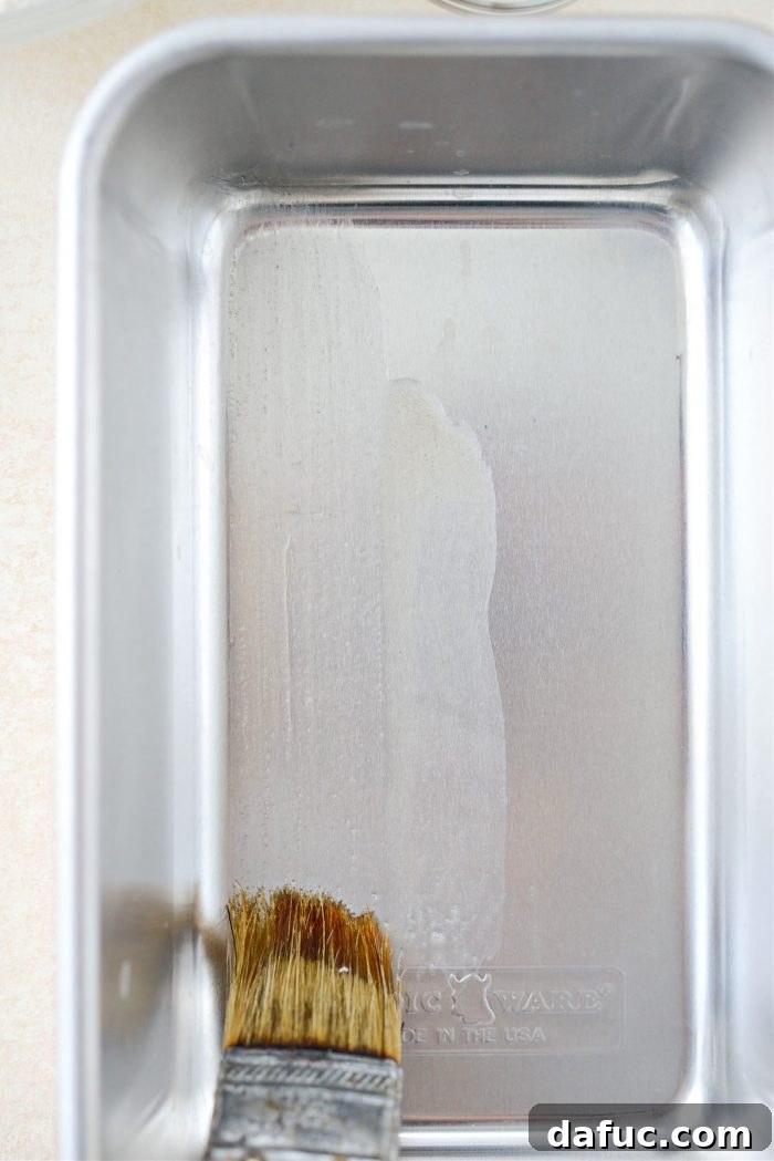 Brushing a large bread loaf pan with melted butter