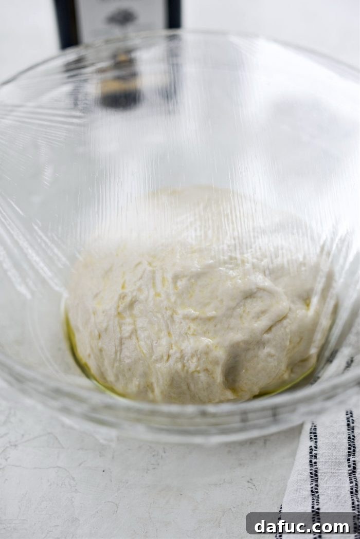 Covering the dough bowl with plastic wrap for rising.