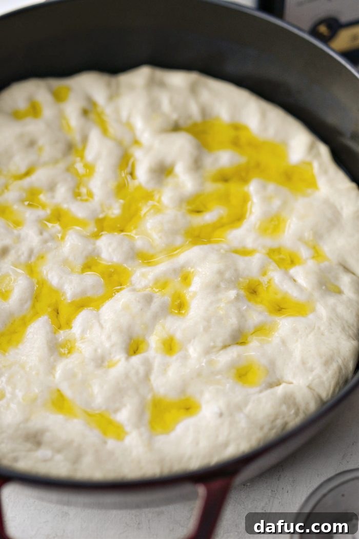Drizzling olive oil and sprinkling flaky sea salt on focaccia dough.