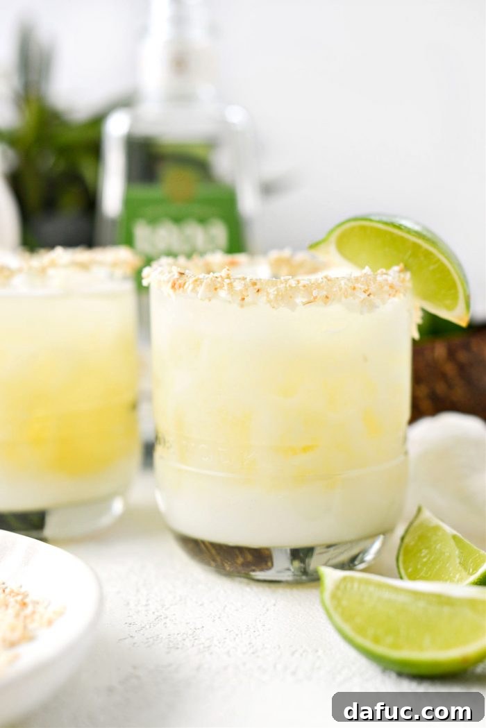 Exquisite Pina Colada Margarita served in a frosted glass with a toasted coconut rim, garnished with a lime wedge