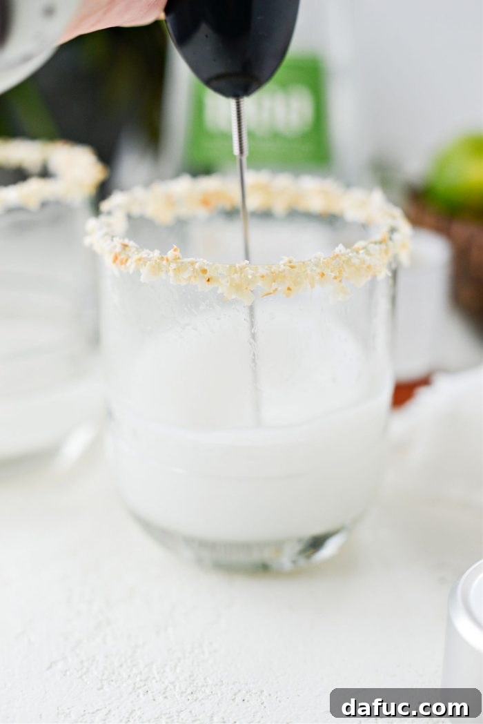 The blended coconut tequila and cream of coconut mixture in the glass, showing a frothy top layer