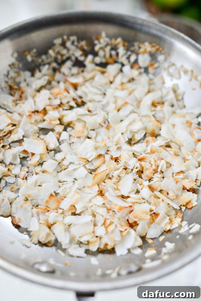 Close-up of toasted coconut flakes in a skillet, showcasing their golden-brown color and inviting texture
