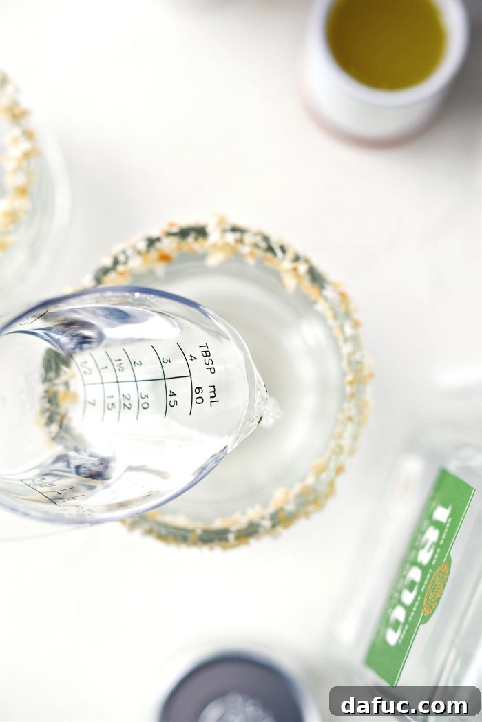 Coconut tequila being poured into a glass already prepared with a toasted coconut rim