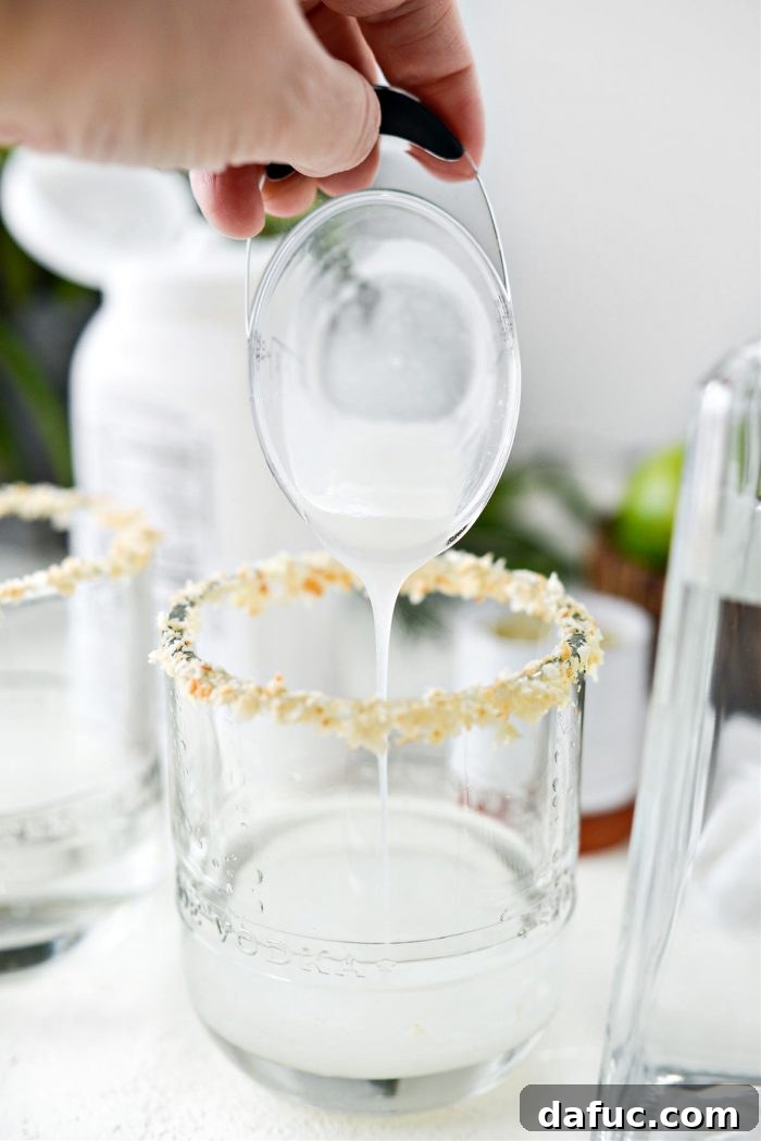 Cream of coconut being poured into the glass with coconut tequila