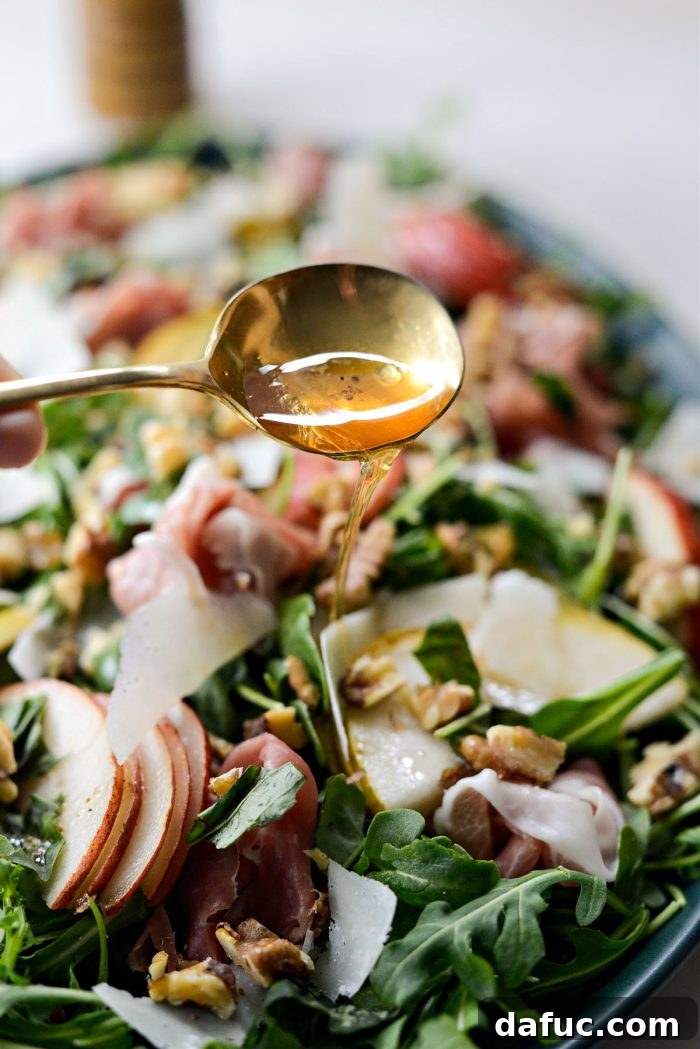 More vinaigrette being drizzled onto the Pear and Prosciutto Arugula Salad